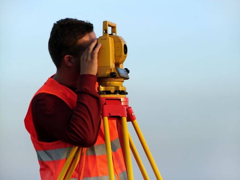 Surveyor using precision equipment to collect topographic survey data for evaluating terrain conditions and future land-use opportunities.