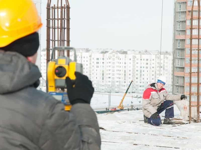 Construction staking survey being performed on an apartment construction site with layout measurements in Rochester New York